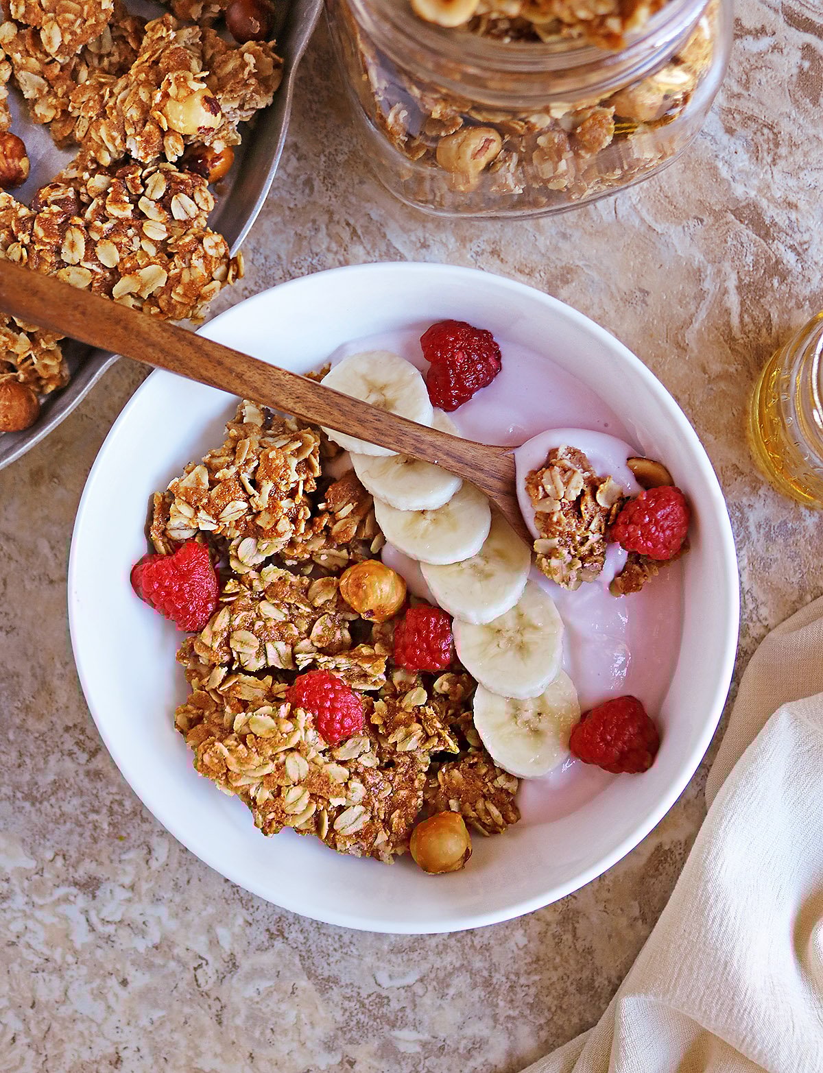 Easy Homemade protein peanut hazelnut granola IN A LARGE WHITE BOWL WITH A BOWN SPOON.