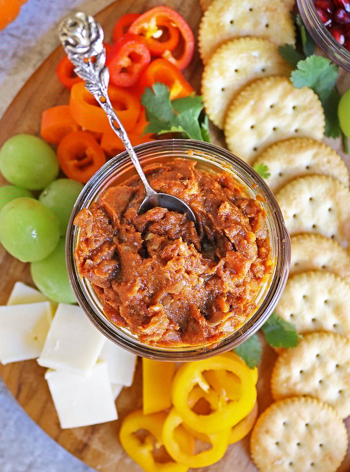 Easy delicious pumpkin chutney in a glass jar on a platter with cheese, crackers and fruit.