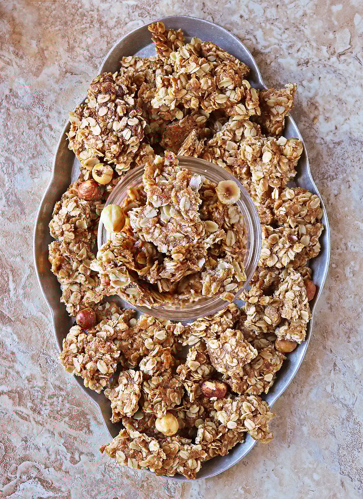 Homemade protein peanut hazelnut granola on a tray on a brwon marble background.