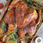 Spatchcock turkey with yogurt and spices on rimmed baking tray.