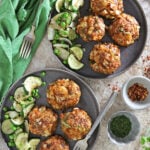 Two plates with Delicious spiced cabbage cakes with some sautéed cucumbers on gray plates with a green napkin.