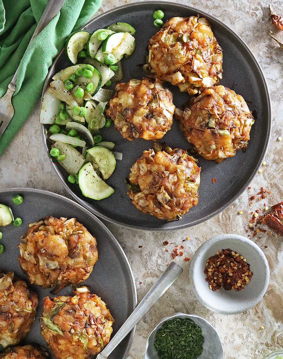 Easy tasty cabbage potato cakes on a gray plate with cucumber and pea salad.