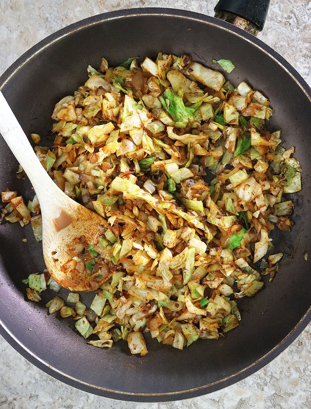 Making a saute with cabbage, onon, ginger, garlic, and spice in a large skillet.