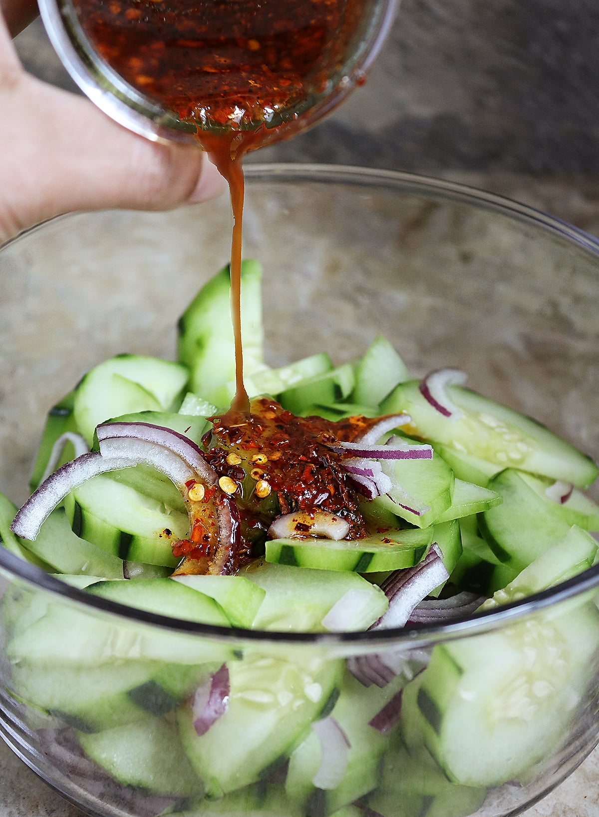 Adding tangy, spicy, sweet, harissa dressing to cucumber onion mix