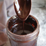 Easy Sugar-free chocolate syrup dripping from a spoon into a jar.