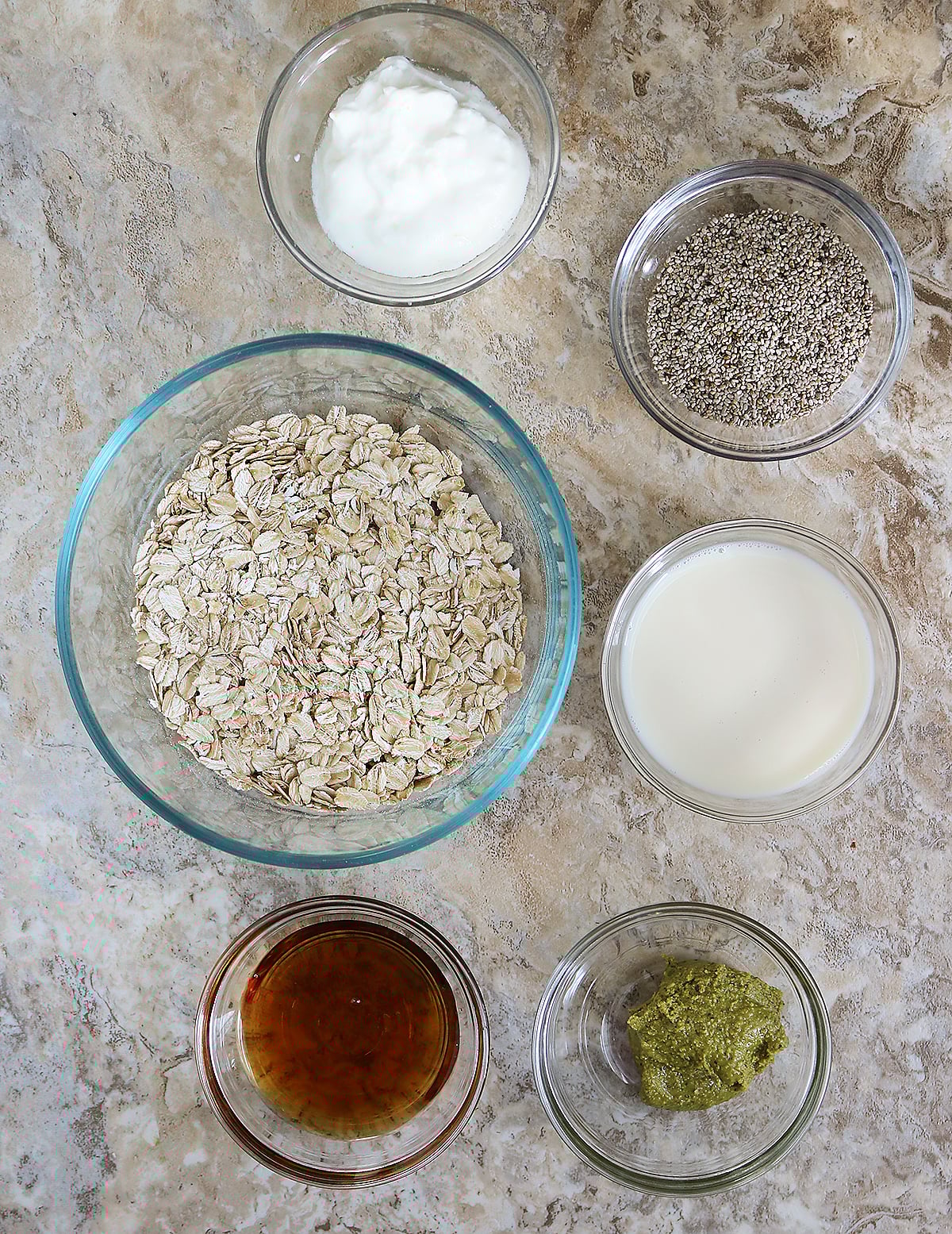 6 Ingredients to make pistachio overnight oats laid out on a gray background.
