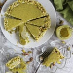 Messy and delicious Pistachio keto no bake cheesecake on a white plate with a few slices on small glass serving plates.