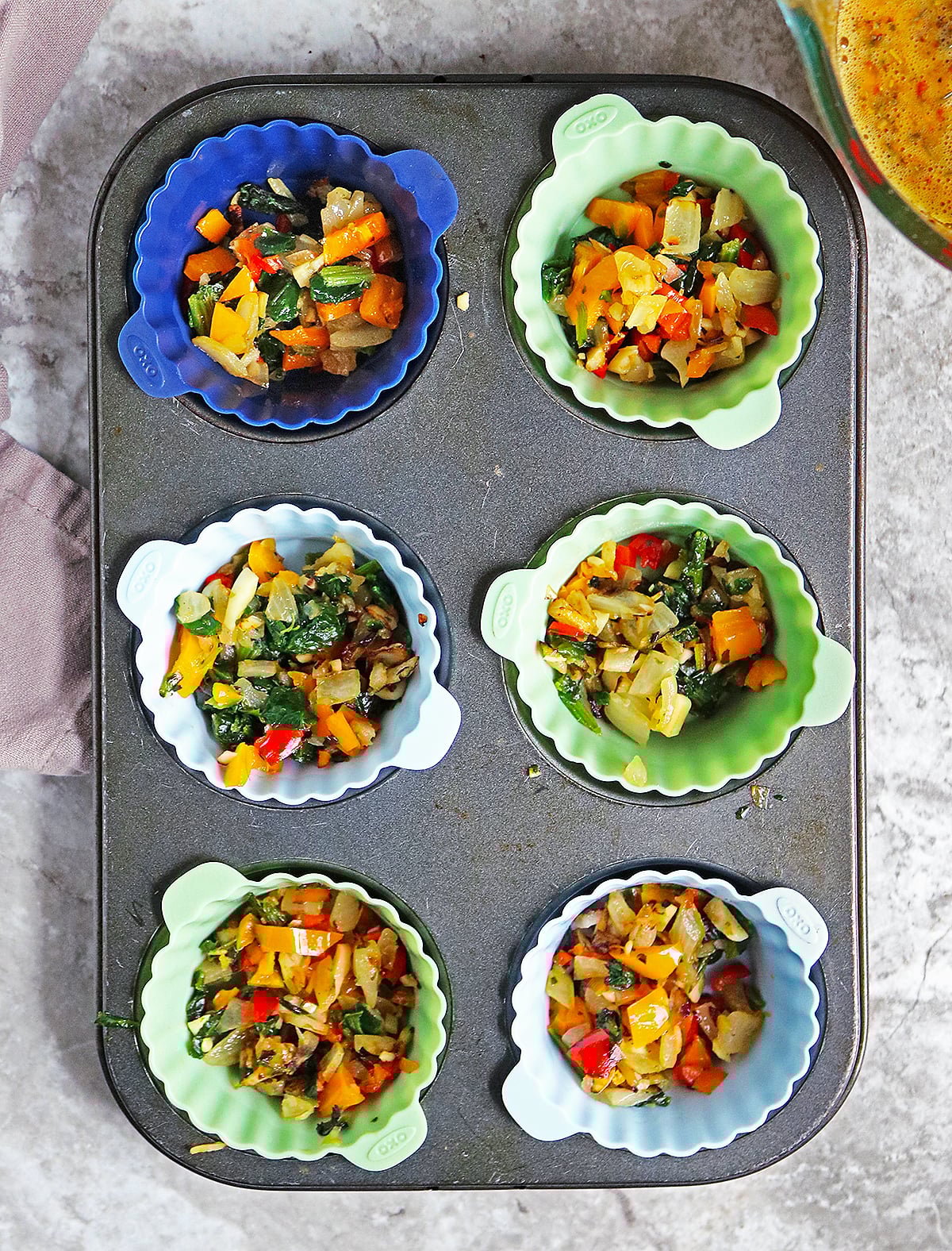 adding onion pepper mixture to muffin cups