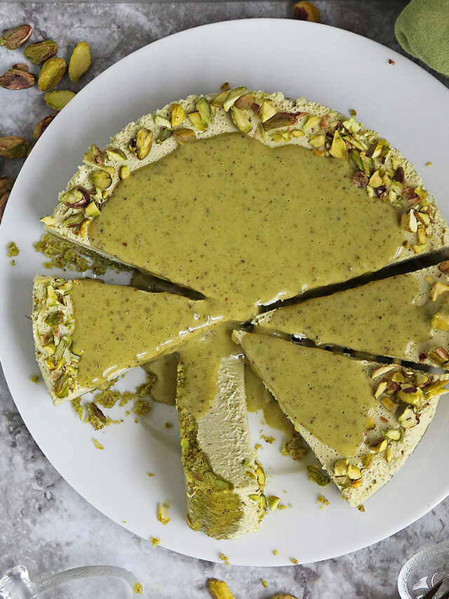 Messy and delicious Pistachio keto no bake cheesecake on a white plate with a few slices on small glass serving plates.