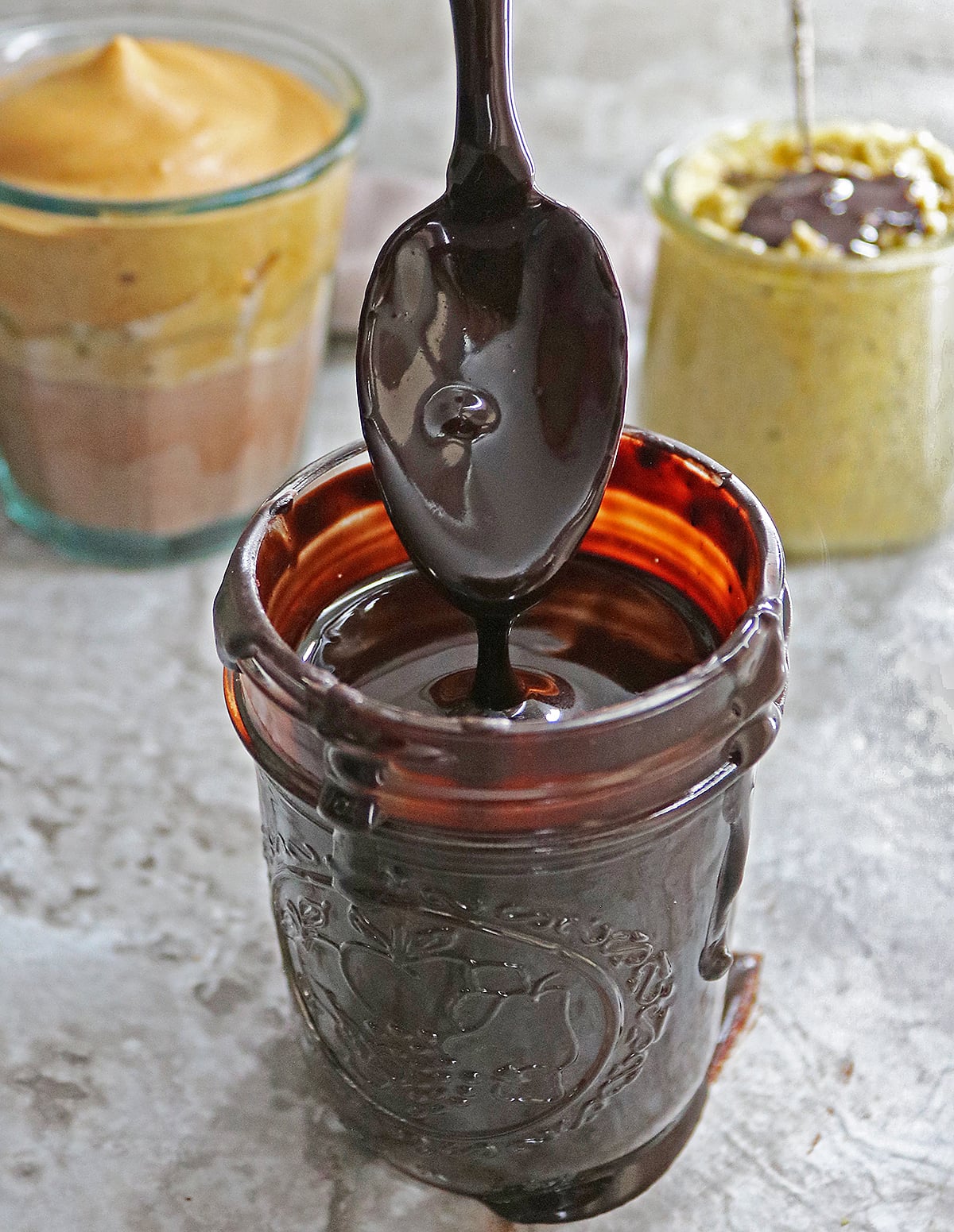 easy 3 ingredient homemade chocolate syrup with coffee and chia pudding in the background.