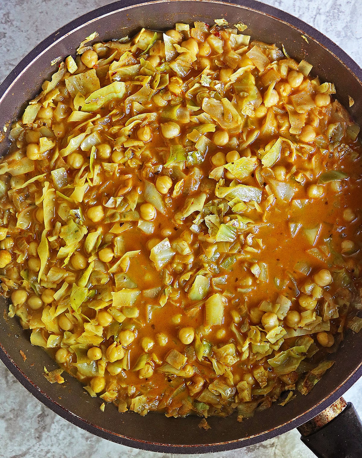 Creamy Cabbage chickpeas simmering in a large pan.