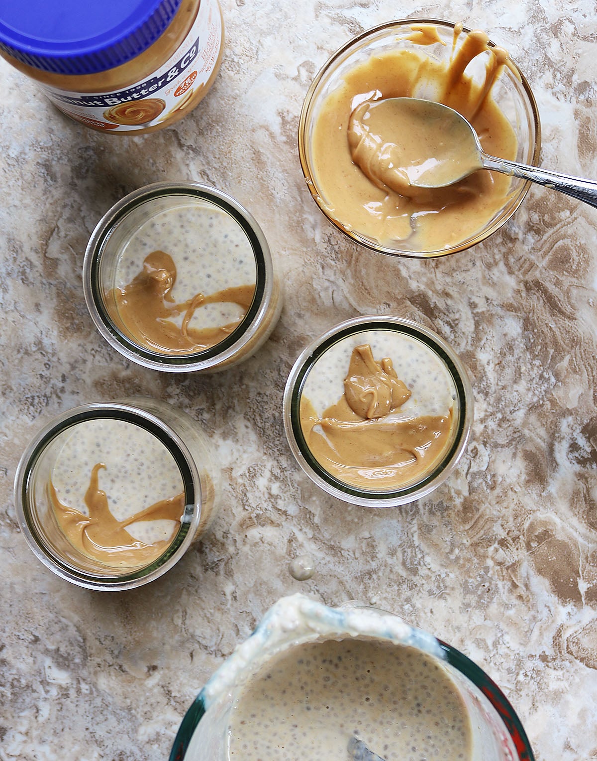 spooning layers of maple peanut butter chia pudding and peanut butter into serving containers