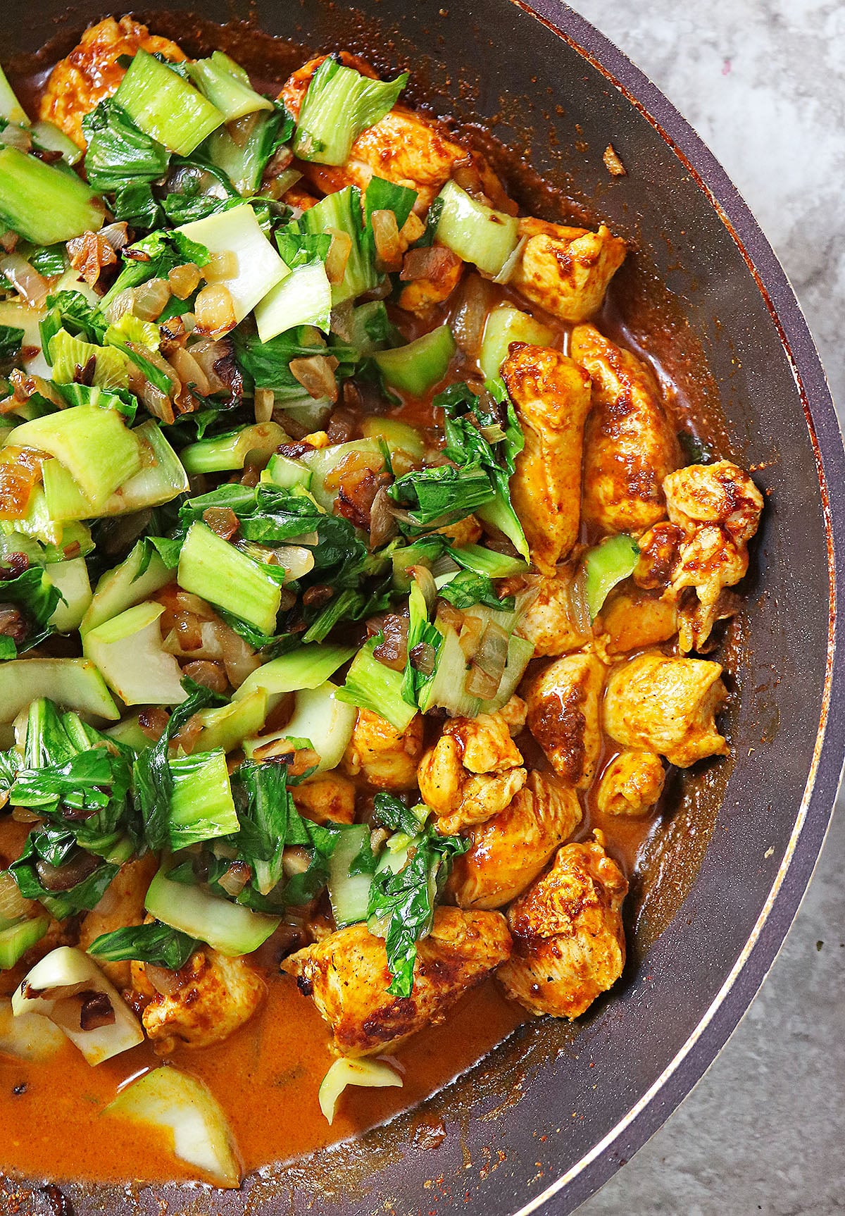 An easy weeknight dinner of chicken and bok choy simmering in a pan