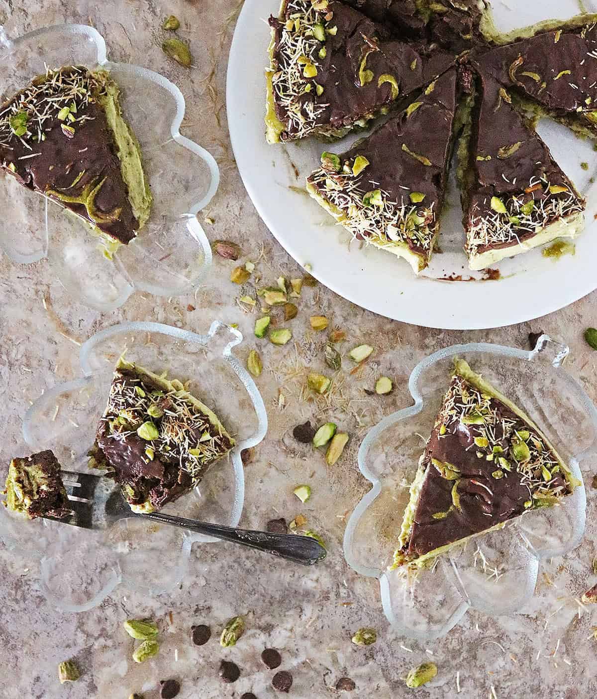 Slices of this No bake dairy-free Dubai chocolate cheesecake on glass serving plates with forks, ready to be enjoyed.