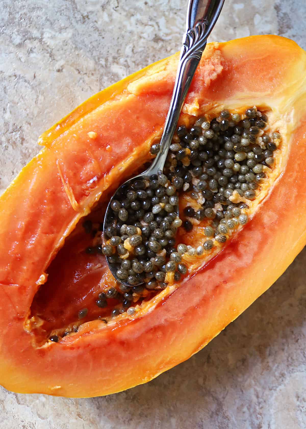 scooping out papaya seeds caviar