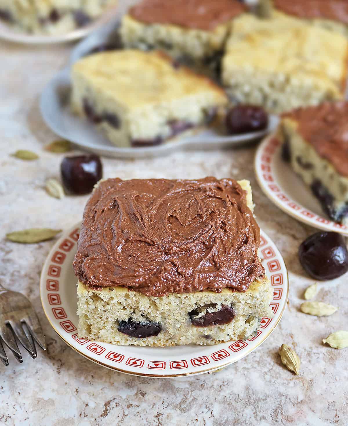 a slice of cherry cardamom cake with small batch dairy-free chocolate frosting - a match that is so amazing