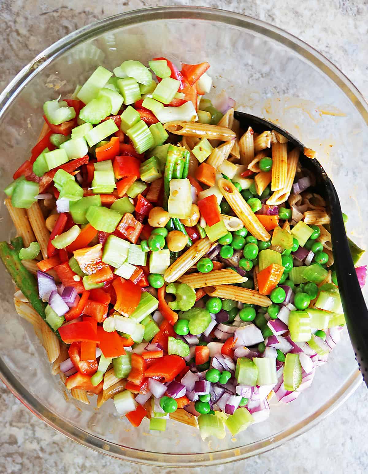 mixing all the veggies together with pasta chickpeas and broccolini