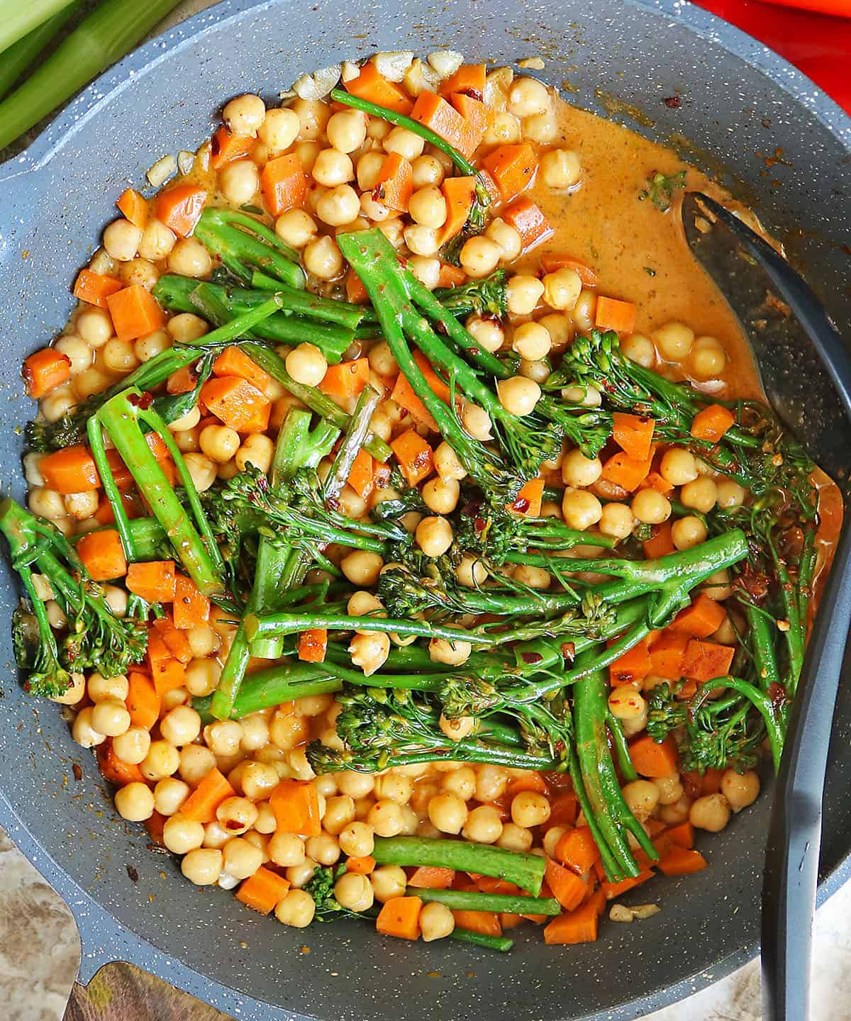 chickpeas, broccolini, carrots, being sautéed with spices and coconut milk