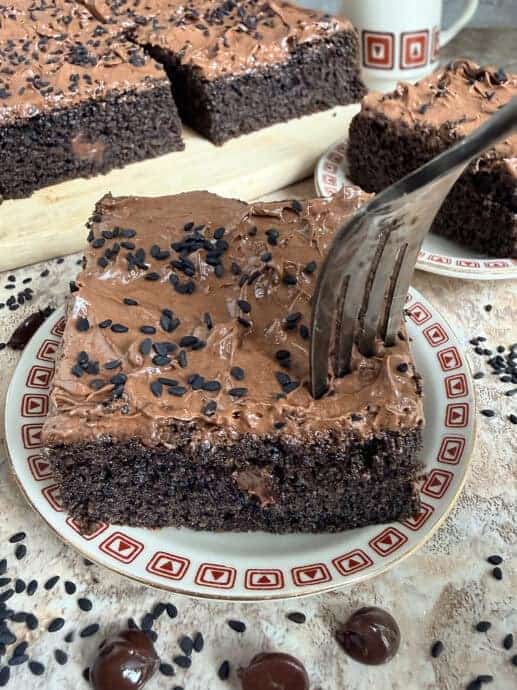 a slice of black sesame chocolate cake with a fork ready to dig into it.