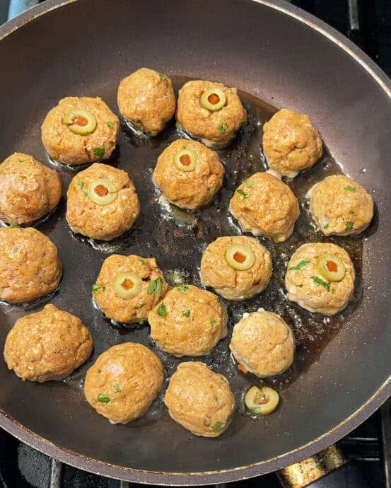 adding some olive eyes to the turkey meatballs