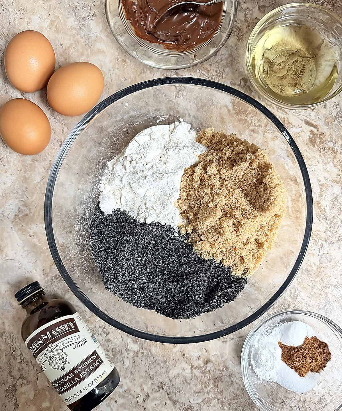 10 ingredients to make this black sesame cake laid out on a brown marble background.