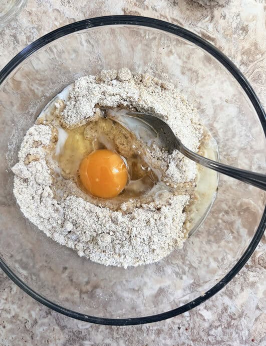 Mixing flour, egg, and butter in a glass bowl for baking.
