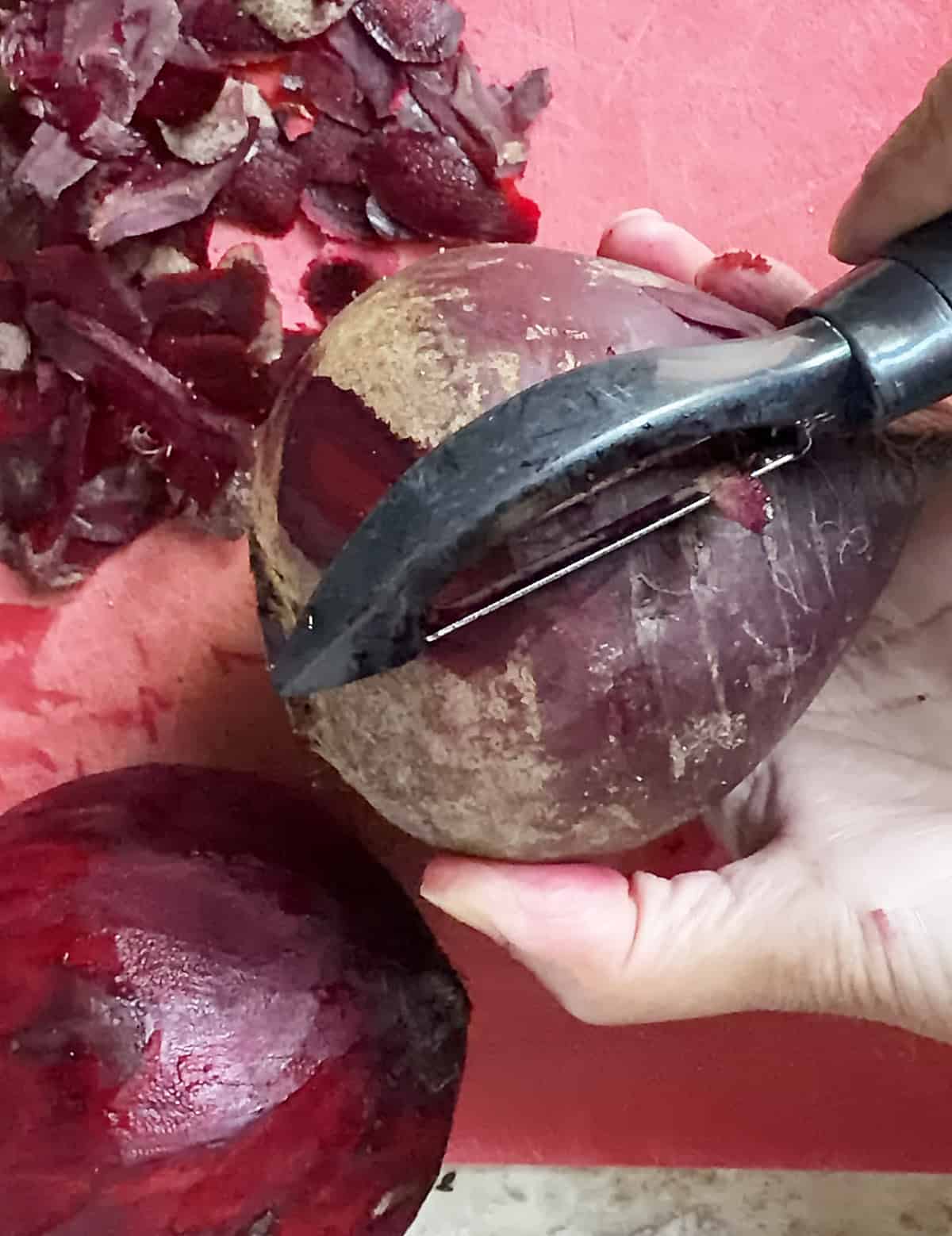 peeling a beetroot on a red board to avoid too much staining.